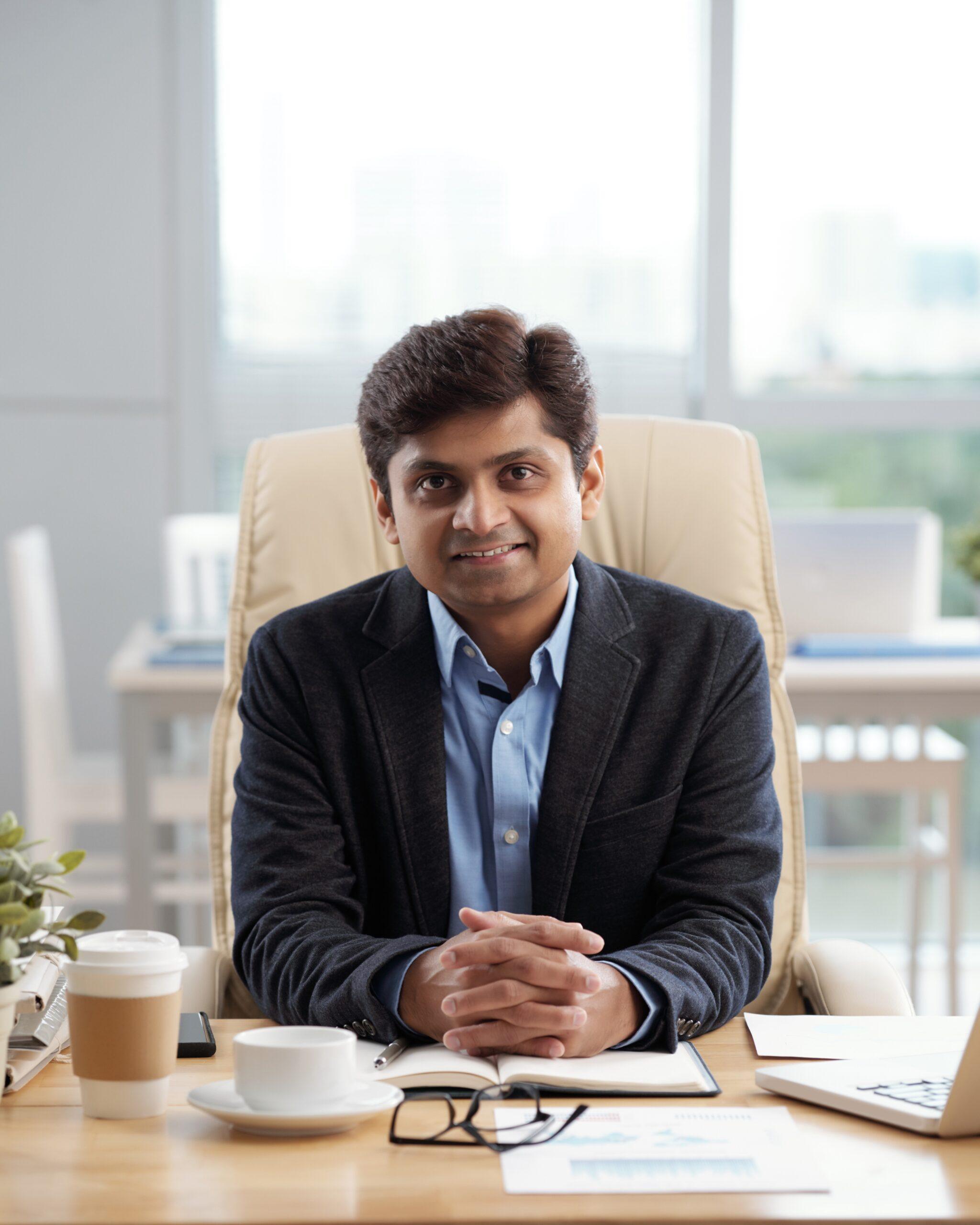 Confident smiling CEO of company sitting at his office table