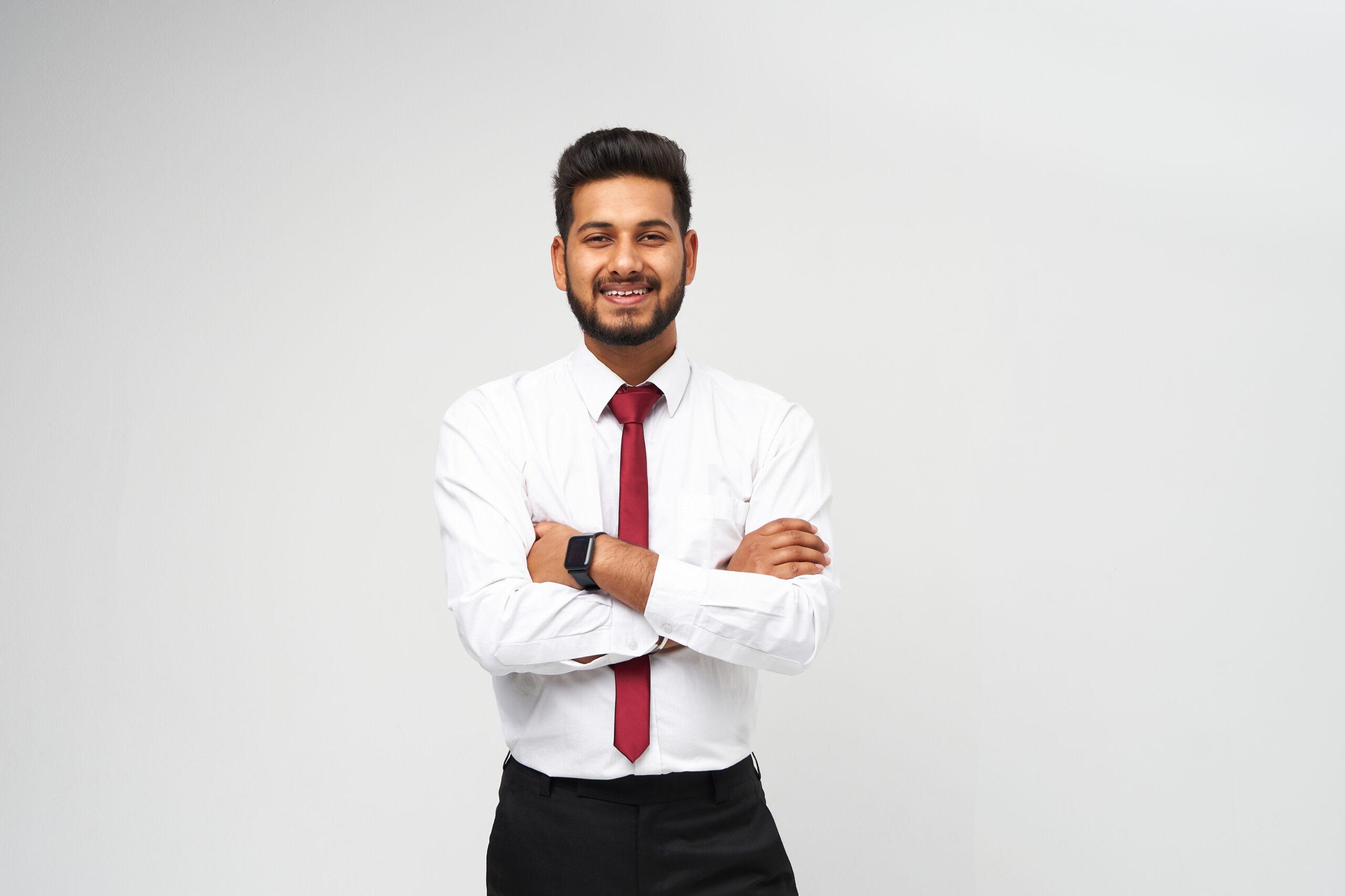 Portrait of young indian top manager in t-shirt and tie crossed arms and smiling on white isolated background